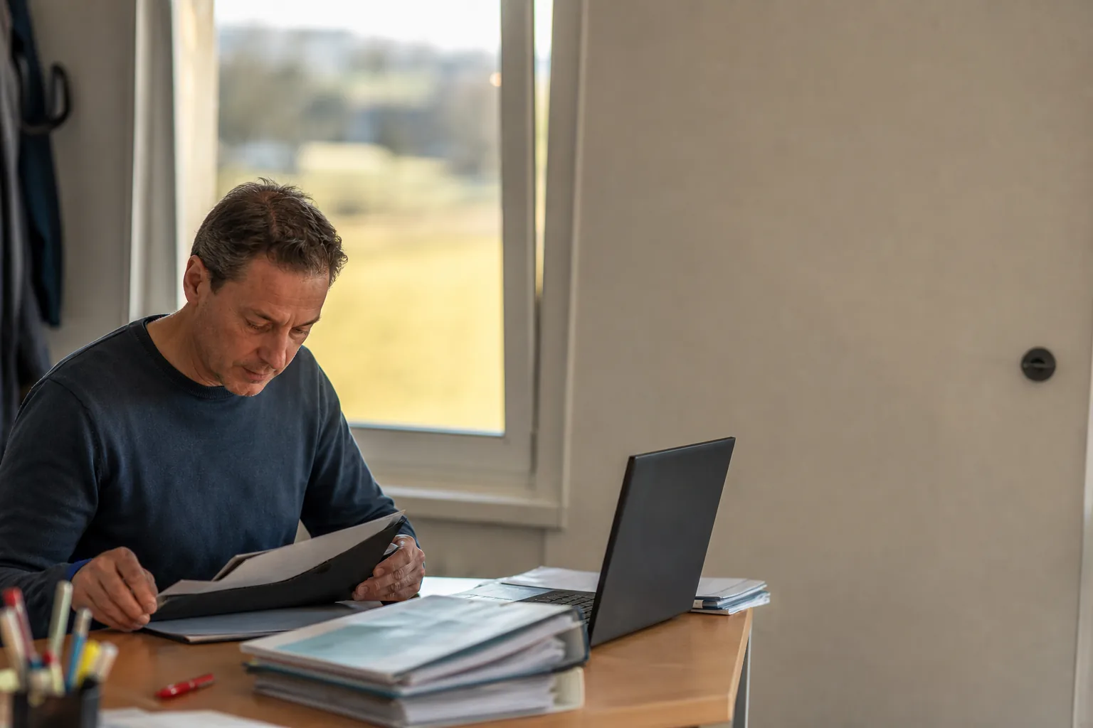Fahrlehrer sortiert Ausbildungsnachweise und arbeitet am Laptop